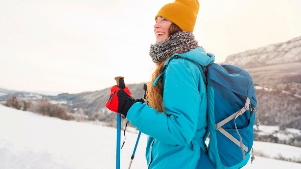 Bilden föreställer en kvinna som är ute och vandrar i bergen under vintern.